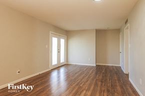 Phoenix house for rent - A room with wooden floors and white walls, with a door and a window.