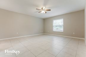 North Port house for rent - an empty living room with a ceiling fan and tiled floors