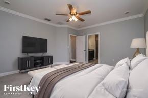 Spring Hill house for rent - A bedroom with a bed, a ceiling fan, and a television.
