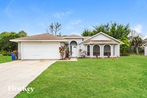 Palm Bay house for rent - a white house with a lawn and a garage