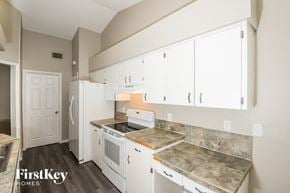 Palm Bay house for rent - a kitchen with white cabinets and white appliances and marble counter tops