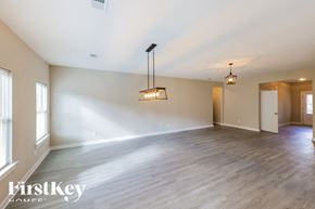 Parrish house for rent - A spacious room with wooden flooring and a large window on the left side.