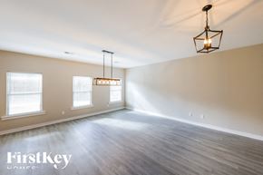 Parrish house for rent - A well-lit, empty room with wooden floors and a hanging light fixture.