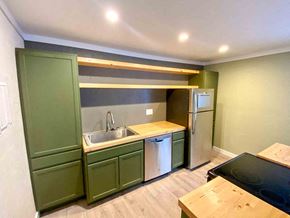 Anchorage apartment for rent - a kitchen with green cabinets and a sink and a refrigerator