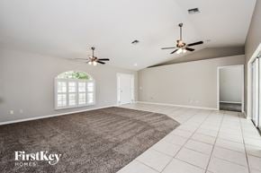 Cape Coral house for rent - an empty living room with two ceiling fans and a rug