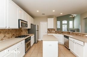 Grand Prairie house for rent - A kitchen with white cabinets and a tiled floor.