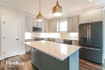 Clayton house for rent - A kitchen with a white island and a black refrigerator.