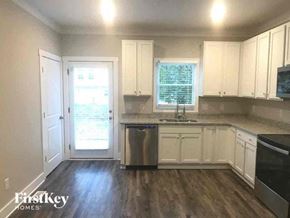 Monroe house for rent - a kitchen with white cabinets and a sink and a door