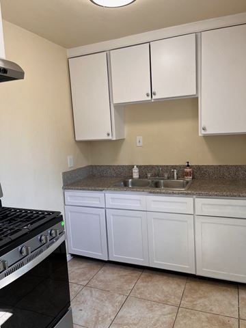 Ontario apartment for rent - a kitchen with white cabinets and a sink and a stove