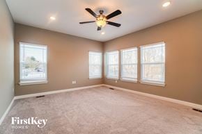 Lancaster house for rent - an empty living room with a ceiling fan and three windows
