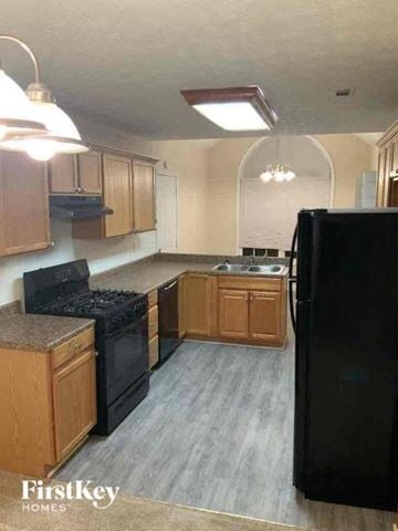 Conyers house for rent - a kitchen with wooden cabinets and a black refrigerator