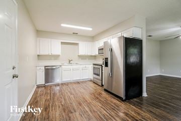 Jacksonville house for rent - a kitchen with white cabinets and a stainless steel refrigerator