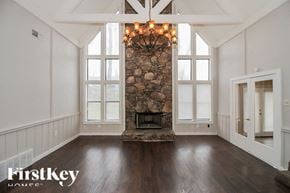 Memphis house for rent - A large, empty room with a stone fireplace and wooden floors.