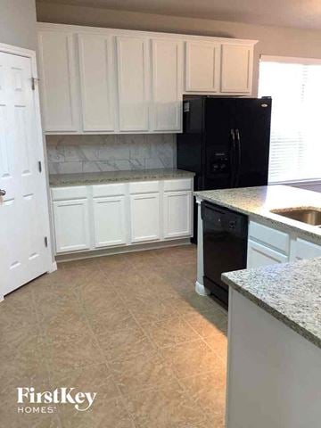 San Antonio house for rent - a kitchen with white cabinets and a black refrigerator