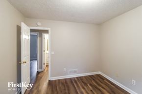 Gainesville house for rent - a bedroom with hardwood flooring and white walls and a door to a hallway