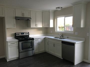 Manteca house for rent - A kitchen with white cabinets and a black dishwasher.