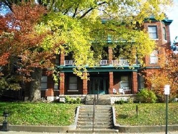 Louisville apartment for rent - a red brick house with a green porch