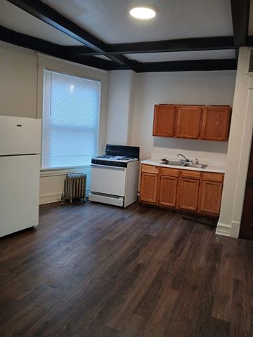 Louisville apartment for rent - A kitchen with a white refrigerator, wooden cabinets, and a white stove top oven.