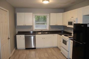 Petal house for rent - A kitchen with white cabinets and black appliances.