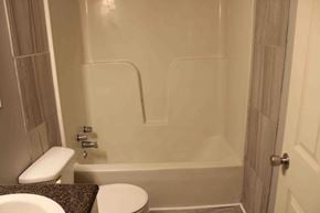 Petal house for rent - A white toilet sits next to a white bathtub in a bathroom.