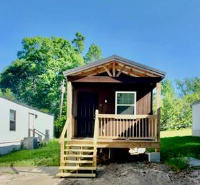 Hattiesburg apartment for rent - A small wooden cabin with a porch and a brown roof.