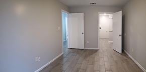 Hattiesburg apartment for rent - A long hallway with white doors and tile flooring.