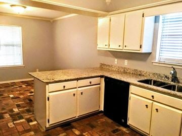Hattiesburg house for rent - A kitchen with a granite counter top and white cabinets.