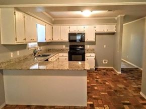 Hattiesburg house for rent - A kitchen with a granite countertop and white cabinets.