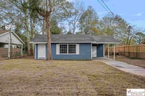 Hattiesburg house for rent - A blue house with a grey roof and a white fence in front.