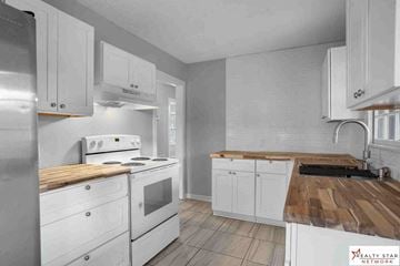Hattiesburg house for rent - A modern kitchen with white cabinets and a wooden countertop.