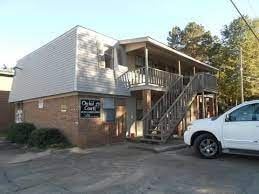 Hattiesburg apartment for rent - A white car is parked in front of a two-story building.