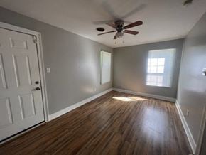 Hattiesburg house for rent - an empty living room with a ceiling fan and wood floors