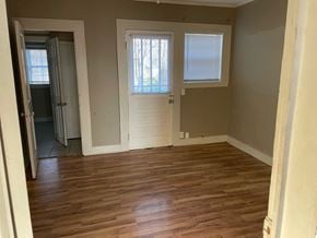 Petal house for rent - an empty living room with wooden floors and a white door