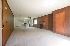 Sumrall house for rent - an empty living room with a fireplace and wooden cabinets
