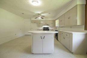 Sumrall house for rent - an empty kitchen with white cabinets and a white counter top