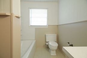 Sumrall house for rent - a bathroom with a toilet and a tub and a window