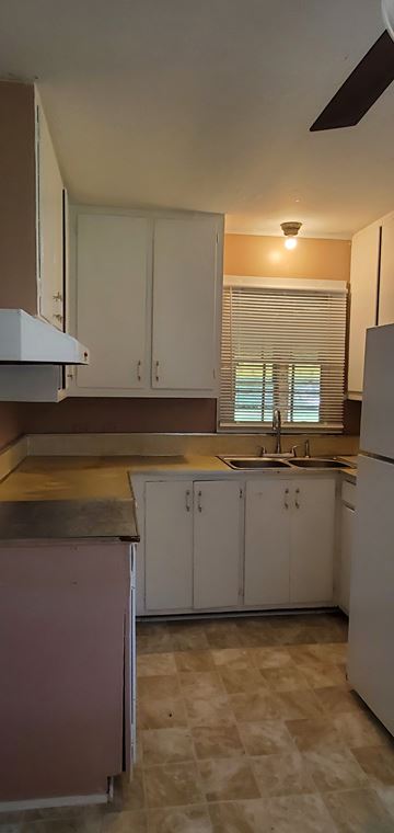 Prentiss house for rent - A kitchen with white cabinets and a pink counter.