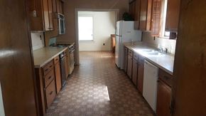 Seminary house for rent - an empty kitchen with wooden cabinets and a tile floor