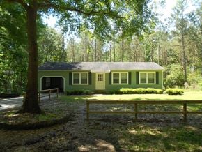 Seminary house for rent - a green house in the woods with a picnic table