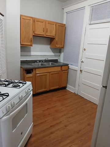 Louisville apartment for rent - a kitchen with a stove and a sink and wooden cabinets