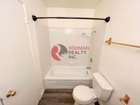 Kelso apartment for rent - A white toilet sits in a bathroom with Rodman Realty Inc. on the wall.