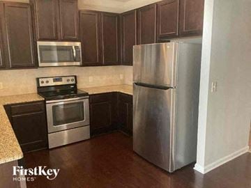 Buford house for rent - A kitchen with a stove top oven, microwave, and refrigerator.