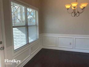 Buford house for rent - A room with a chandelier, a window with blinds, and a door.