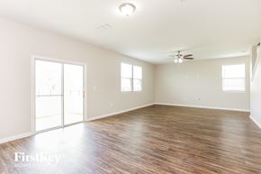 Jacksonville house for rent - A spacious room with wooden flooring and a ceiling fan.