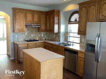 Mansfield house for rent - a kitchen with wooden cabinets and a refrigerator and a sink
