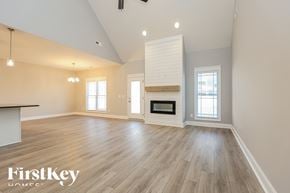 Clarksville house for rent - A spacious room with wooden floors and a fireplace is shown.