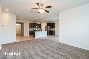 Waxahachie house for rent - A spacious living room with a carpeted floor and a ceiling fan.