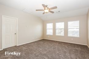 Cypress house for rent - a bedroom with carpet and a ceiling fan and three windows