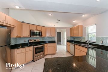 Cape Coral house for rent - a kitchen with black counter tops and wooden cabinets
