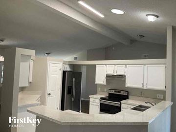 Jacksonville house for rent - a kitchen with white cabinets and a stove and a refrigerator